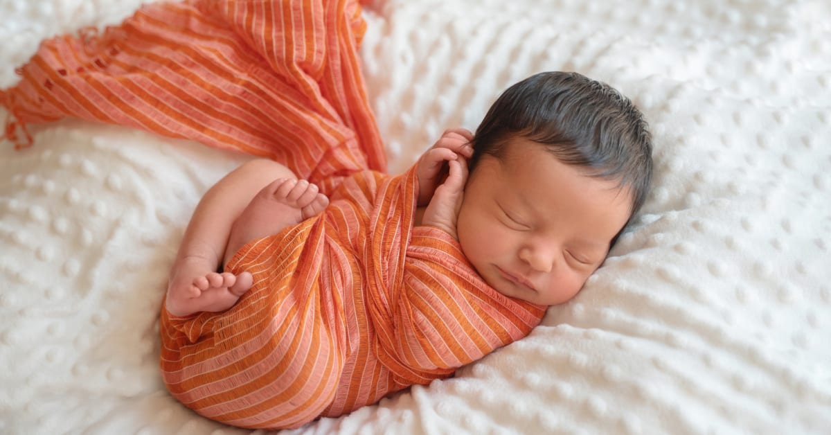 New baby swaddled in orange cloth.