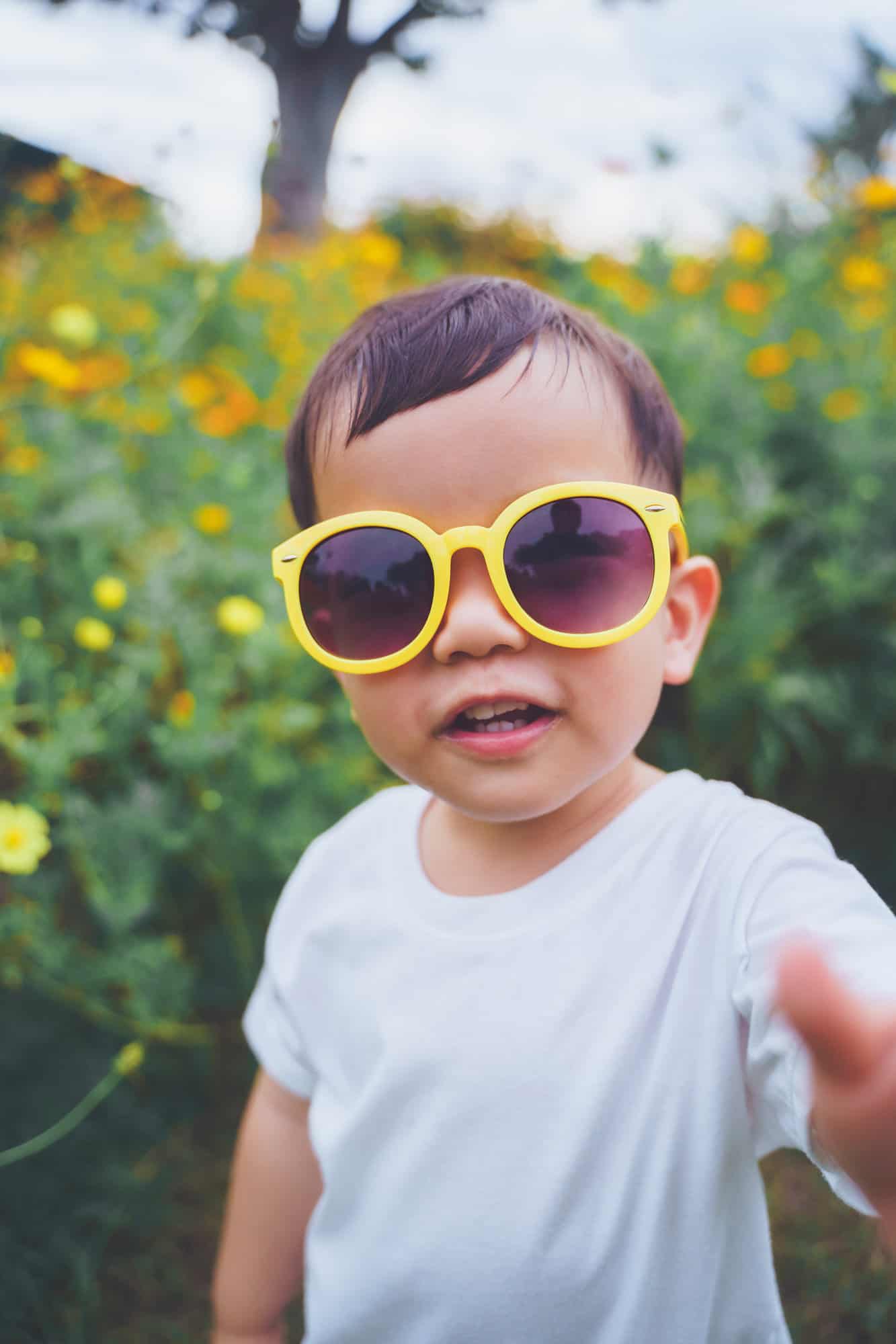 Portrait of Happy smiling Asian Japanese little child boy wearing yellow sunglasses outdoor. looking at camera.