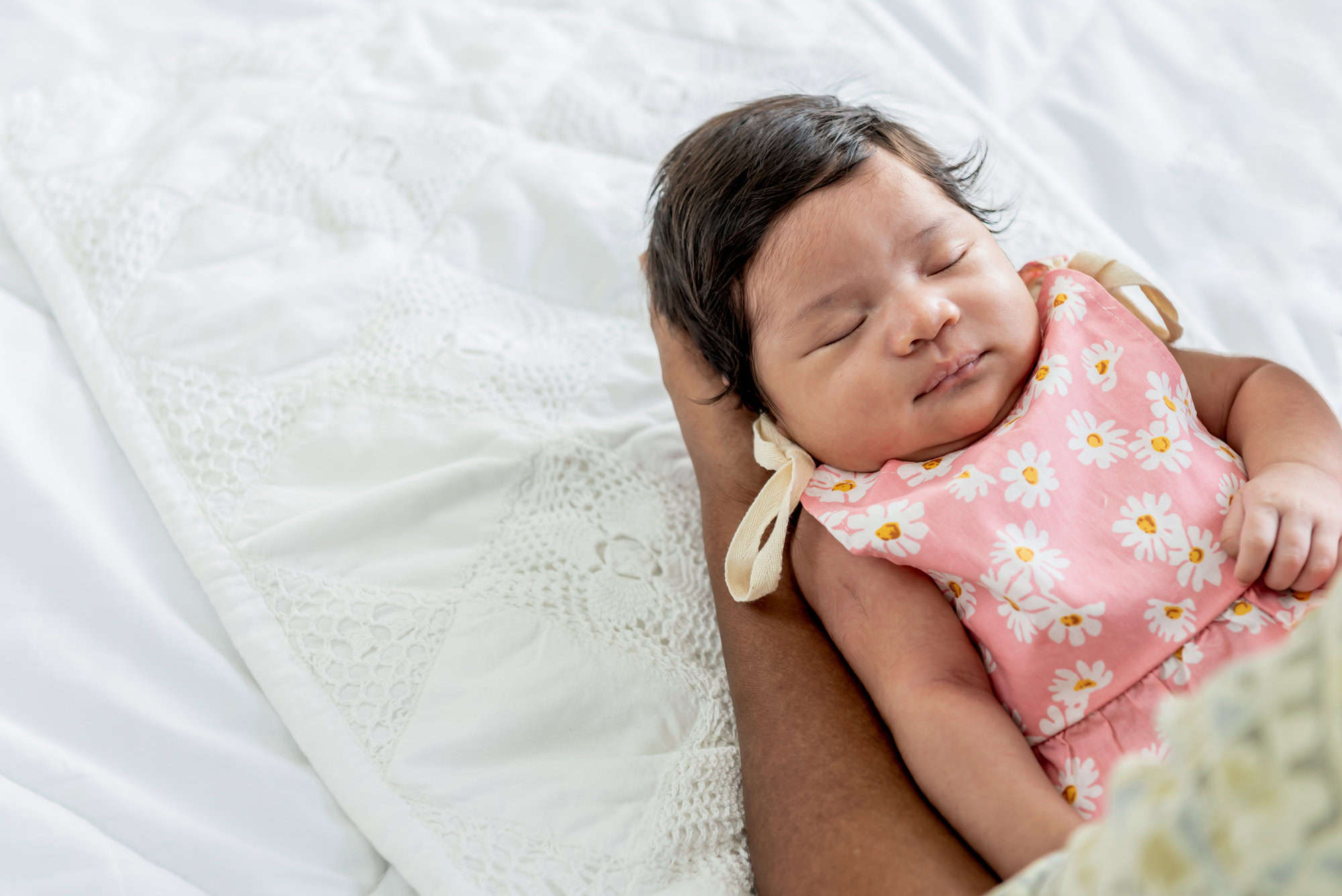 a baby newborn daughter, is 1-months-old and is half Thai half Nigerian, sleeping well on the hands of father, in the bed, to relationship of family and newborn concept.
