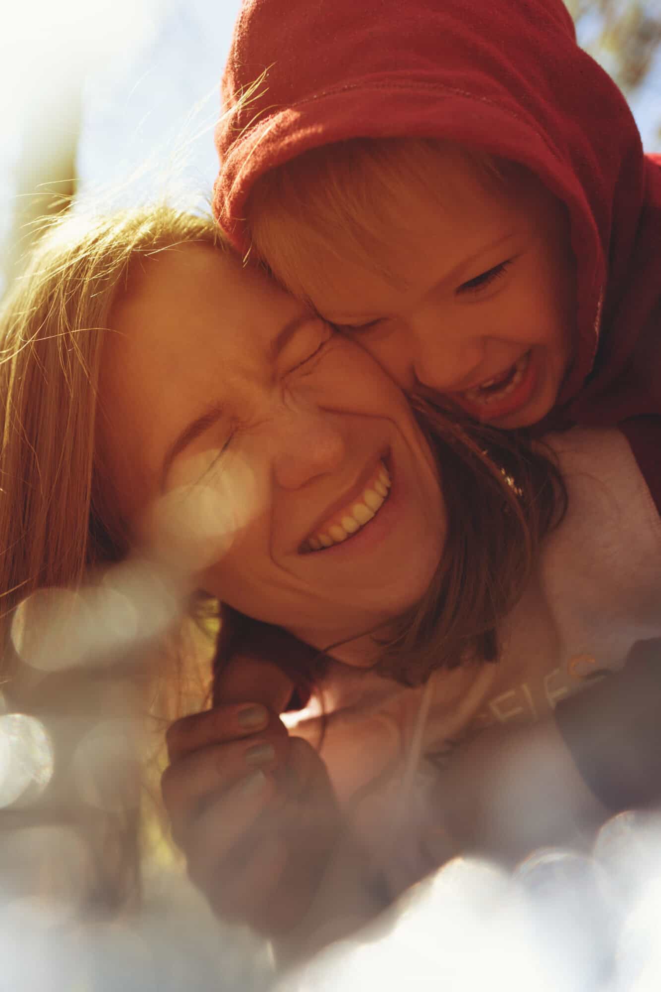 Portrait of smiling mother and son playing together in park. Little son hugging his young mom, having fun together. Happy family concept.