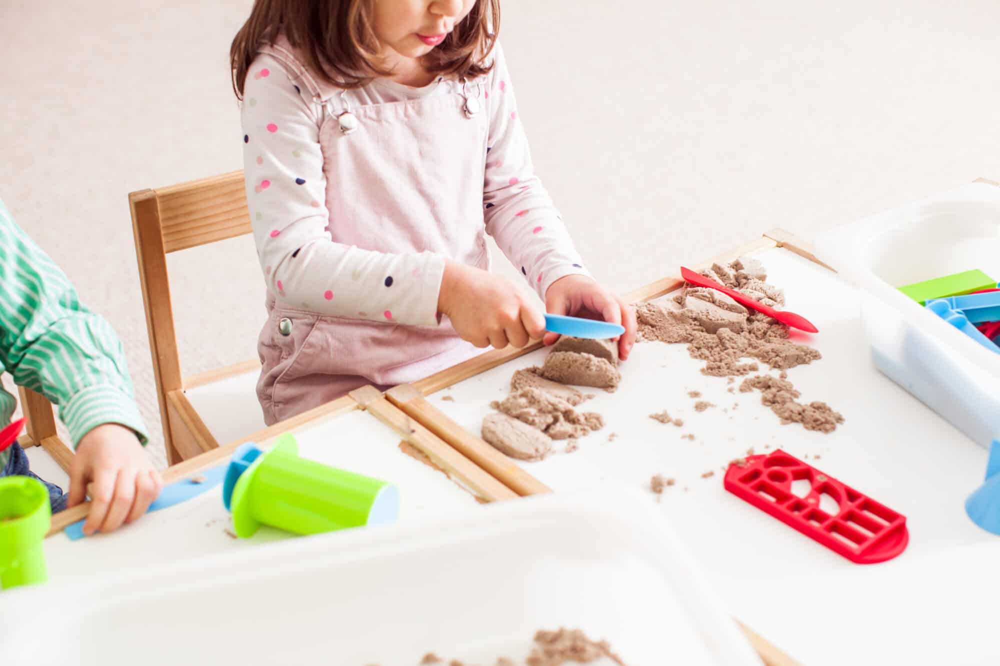 5 years old girl plays with kinetic sand in the kindergarten