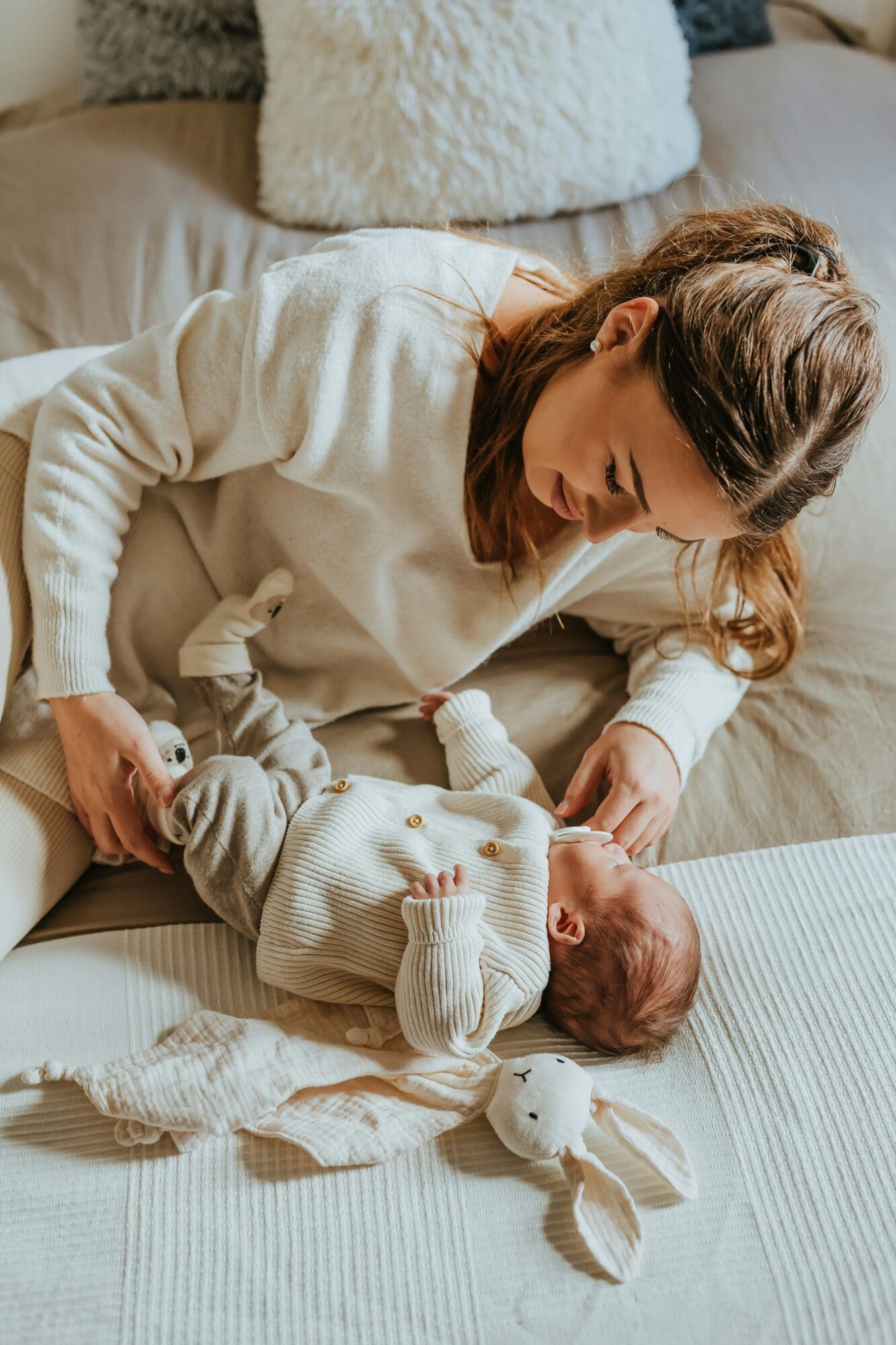 Mom laying next to newborn baby on bed while she gazes at him.