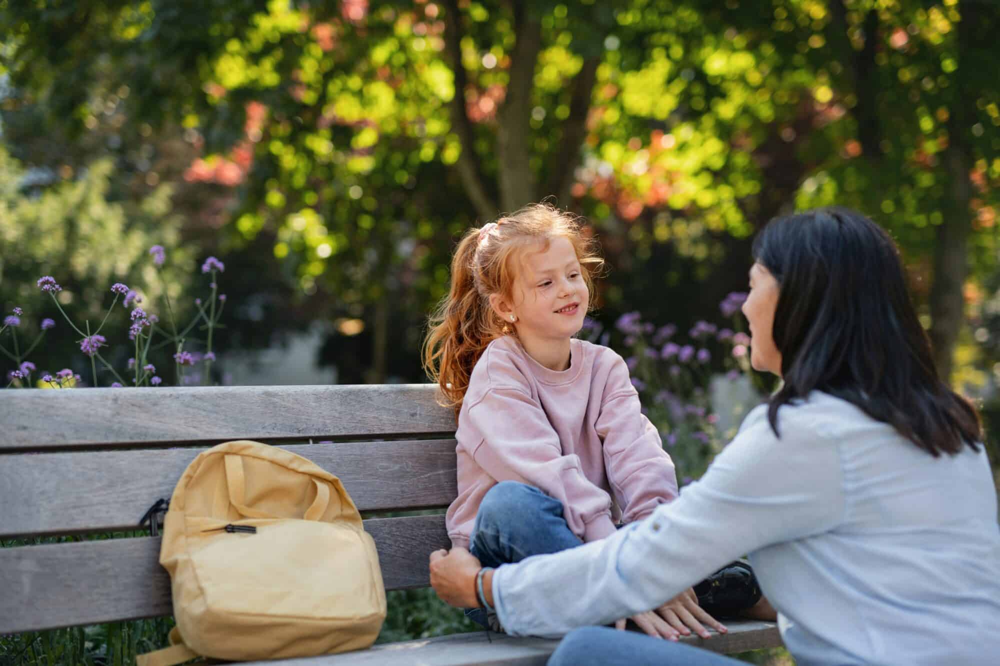 Mom talks one on one with daughter outdoors and gets down to her level.